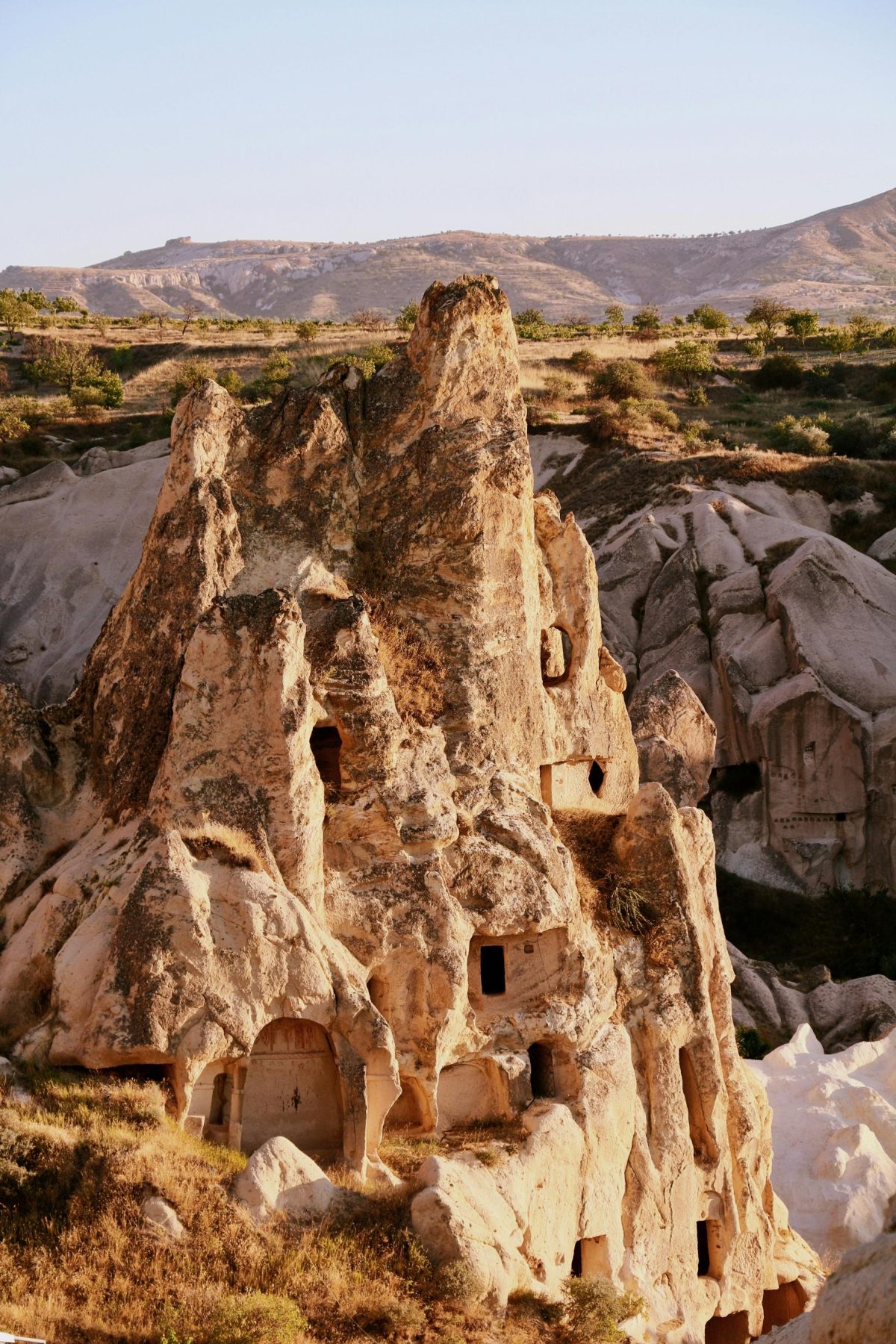 Een rotsformatie in Cappadocië met op de achtergrond een groen landschap.