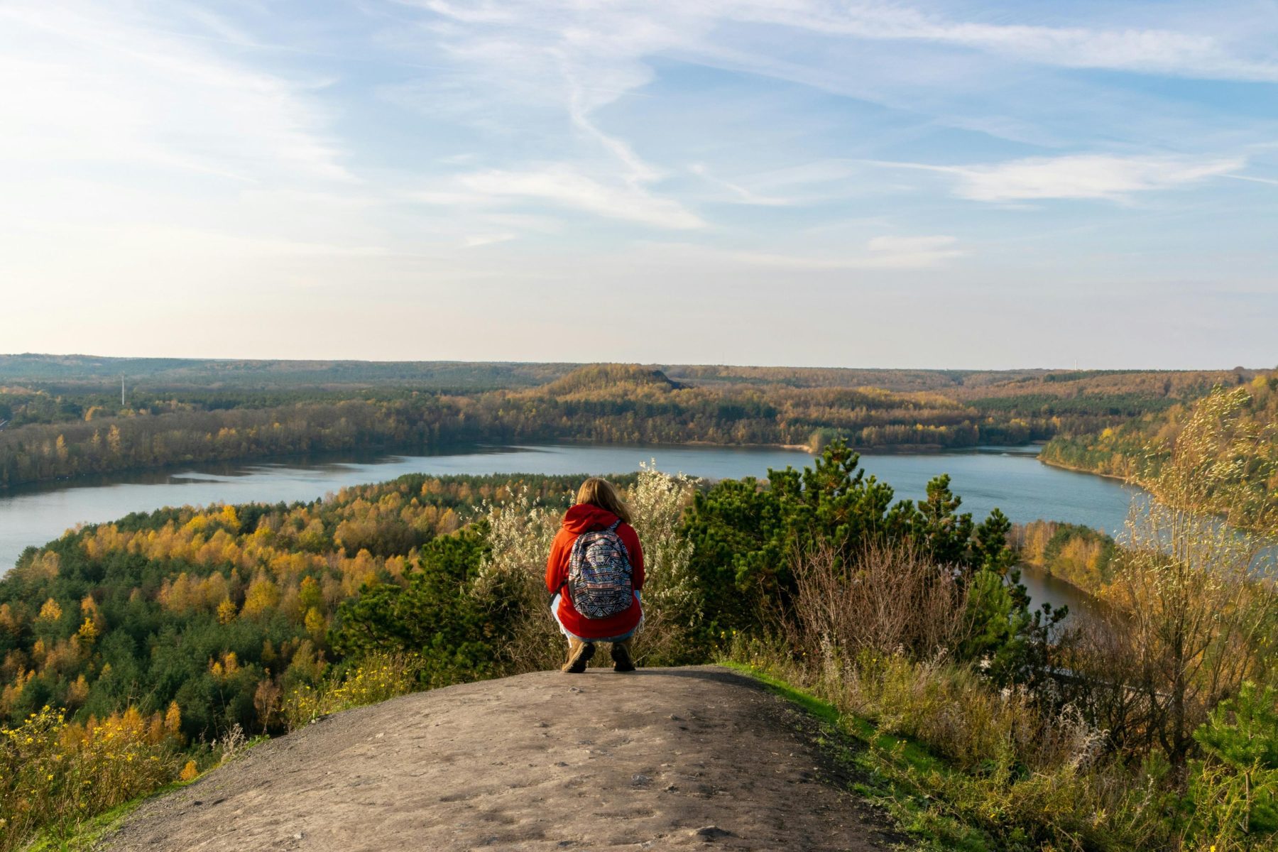 Een persoon kijkt uit over een natuurlandschap in België, wat één van de landen is waar een aantal van de Wandelroutes van het Jaar 2025 zich bevinden.